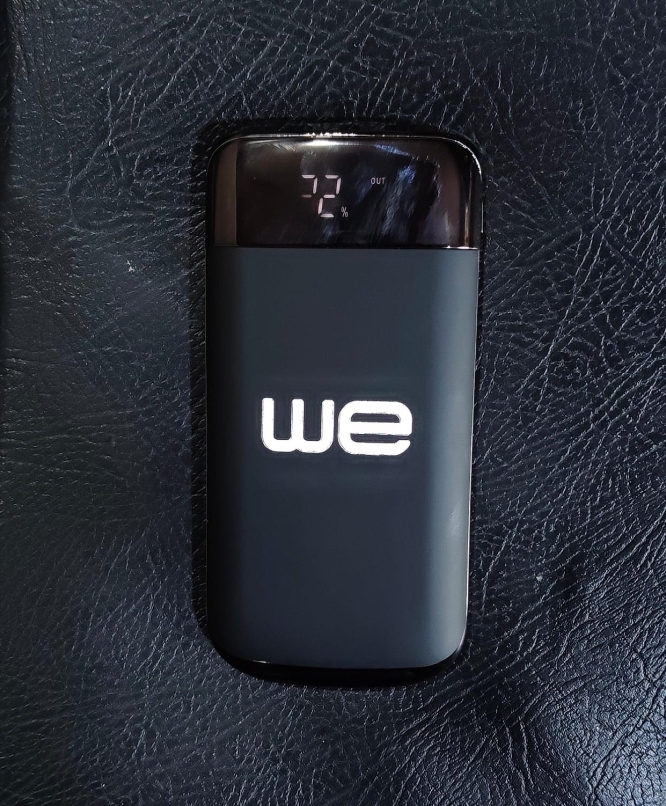 Black powerbank with a glowing WE logo and charge display